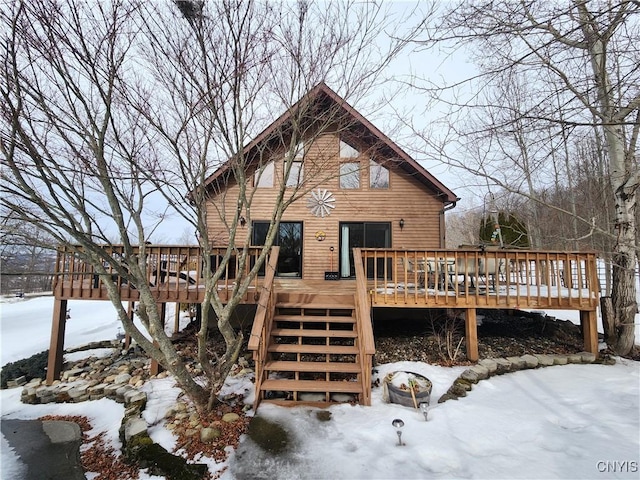 snow covered rear of property featuring stairway and a deck