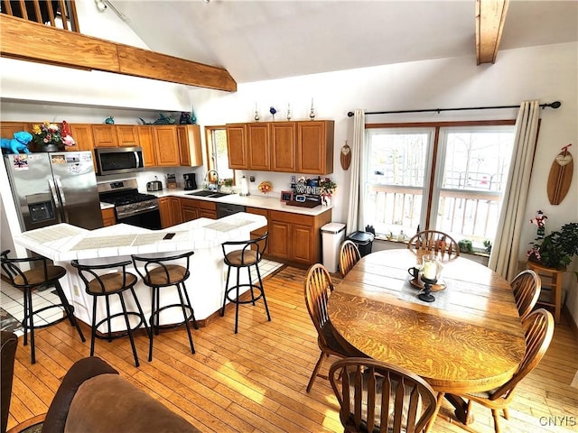 kitchen with light wood finished floors, a breakfast bar area, stainless steel appliances, light countertops, and a sink