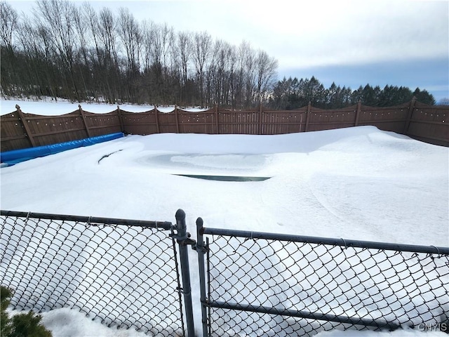 yard covered in snow with a fenced backyard and a gate