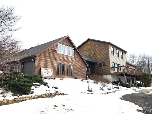 snow covered house featuring an attached garage