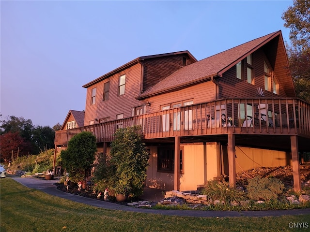 back of house featuring a shingled roof and a deck