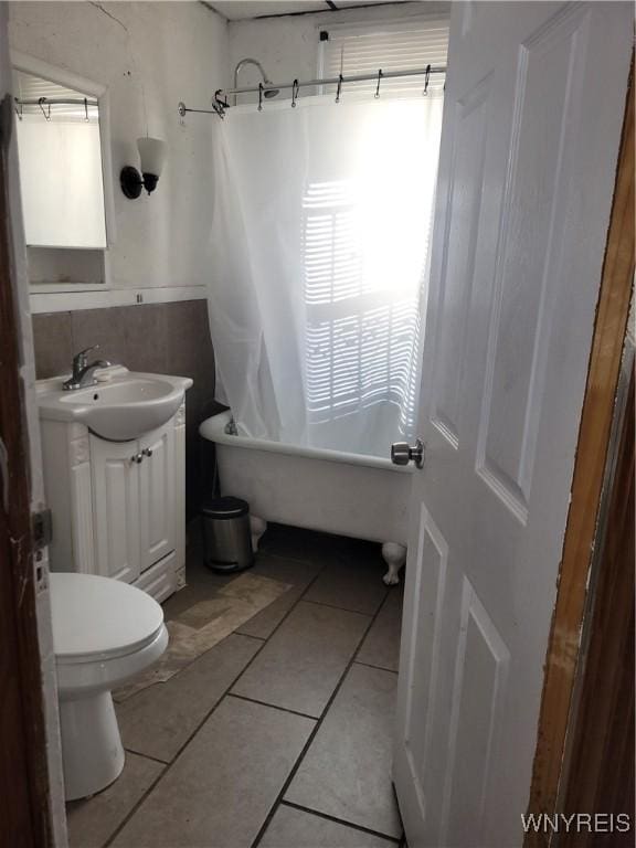 bathroom with toilet, tile patterned flooring, a washtub, and vanity