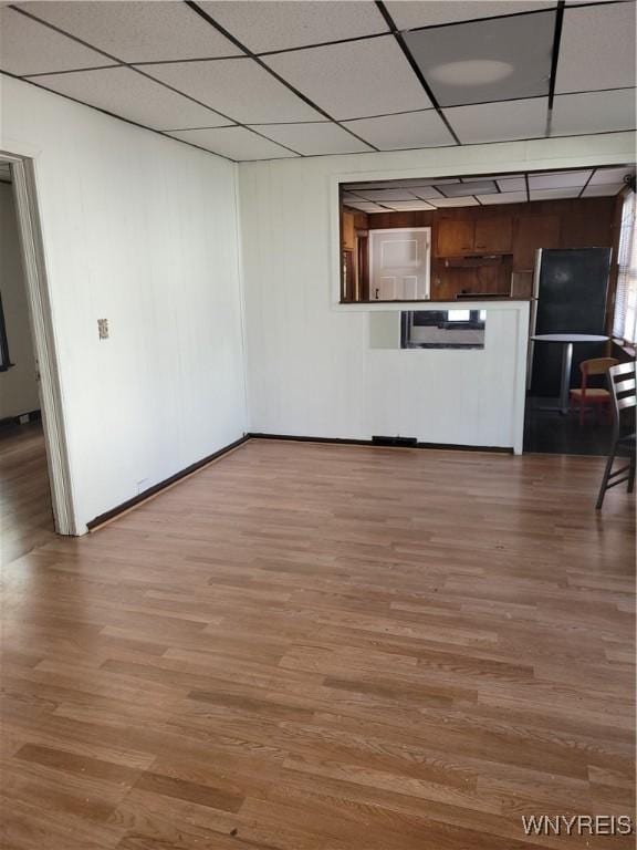 interior space with a paneled ceiling, baseboards, and wood finished floors