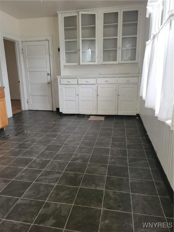 interior space featuring light countertops, dark tile patterned flooring, glass insert cabinets, and white cabinets