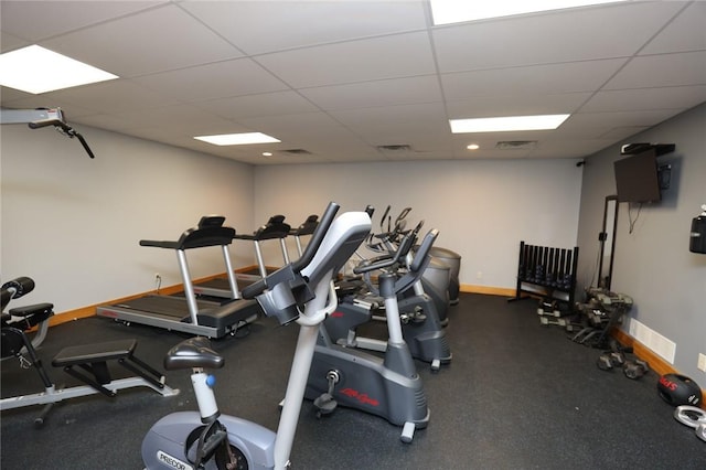 workout area featuring visible vents, a paneled ceiling, and baseboards