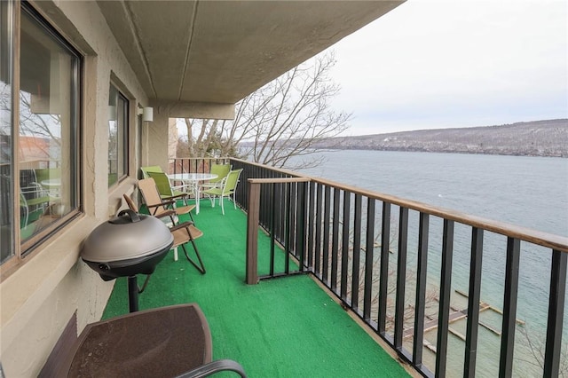 balcony with a sunroom, a water view, and a grill