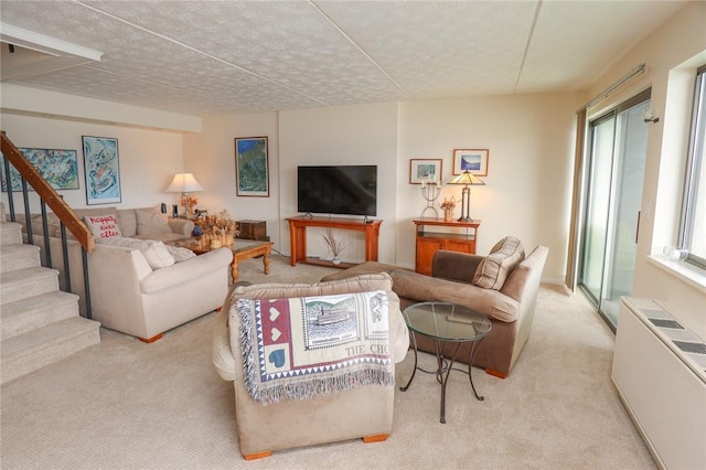 carpeted living area featuring stairs, a textured ceiling, and radiator