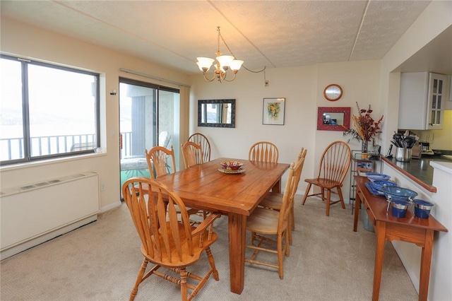 dining room with a chandelier, radiator, light colored carpet, and a textured ceiling