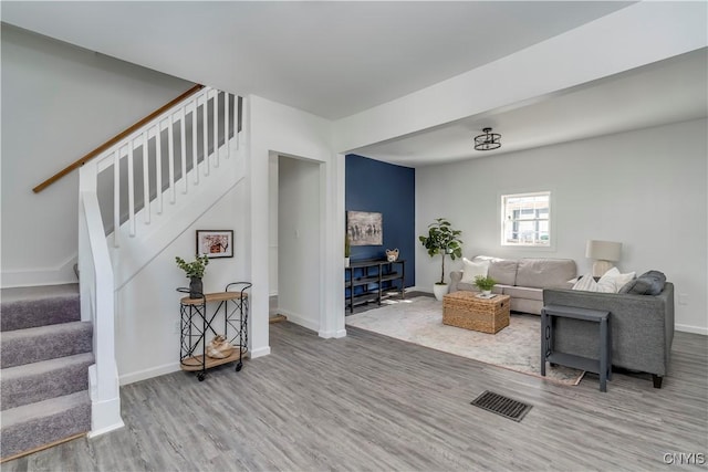 living area featuring stairway, baseboards, visible vents, and wood finished floors