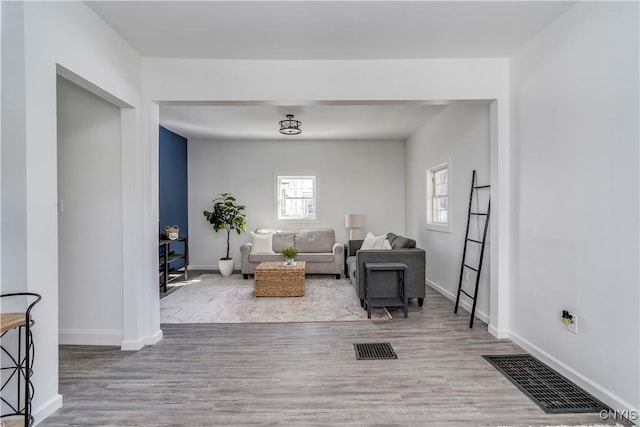 living room featuring wood finished floors, visible vents, and baseboards