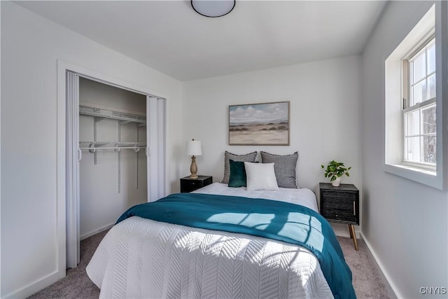 carpeted bedroom featuring baseboards and a closet