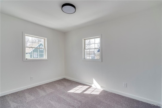 spare room featuring a wealth of natural light, carpet flooring, and baseboards