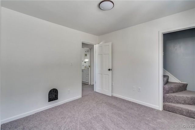 carpeted spare room with baseboards and stairway