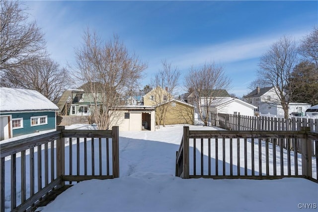 yard covered in snow with an outbuilding and fence