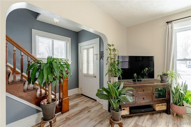 entrance foyer with stairs, a wealth of natural light, and wood finished floors