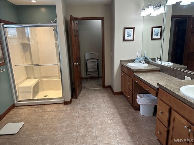 full bathroom featuring a stall shower, a sink, baseboards, and double vanity