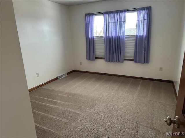 carpeted spare room with visible vents and baseboards