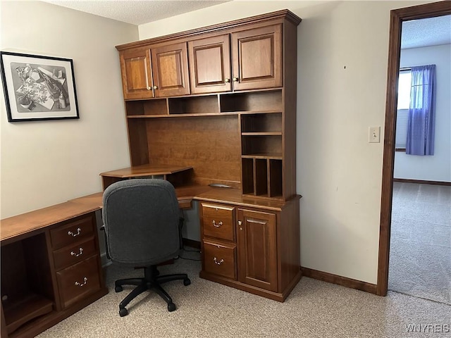 office area with light carpet, baseboards, and a textured ceiling