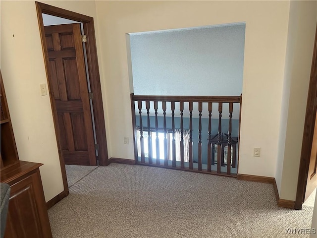 hall featuring carpet flooring and baseboards