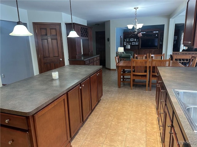 kitchen with dark countertops, a center island, a chandelier, pendant lighting, and a sink