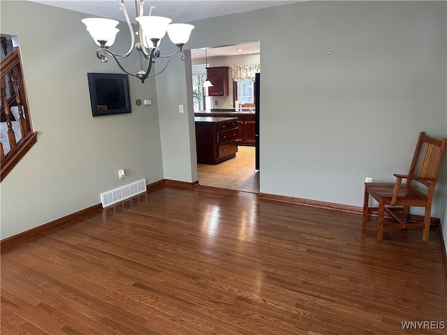 dining space with baseboards, visible vents, an inviting chandelier, and wood finished floors