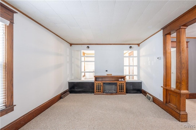 interior space with baseboards, a glass covered fireplace, visible vents, and crown molding