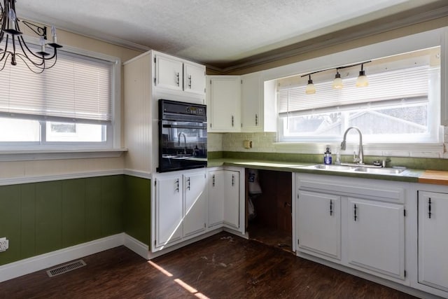 903 W 1st St, Elmira, NY 14905 - kitchen featuring oven, dark wood finished floors, a chandelier, white cabinets, and decorative backsplash