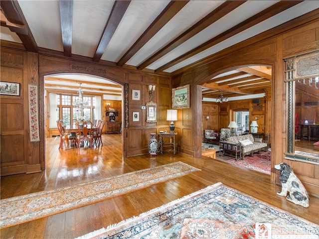 interior space featuring hardwood / wood-style flooring, arched walkways, a notable chandelier, and beamed ceiling