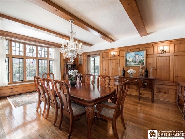 dining room with a notable chandelier, beamed ceiling, and wood finished floors