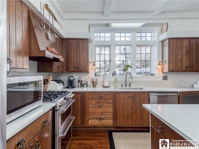 kitchen with beam ceiling, dark wood-style flooring, stainless steel appliances, and a sink