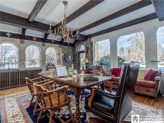 dining space featuring a notable chandelier, beam ceiling, and wood finished floors