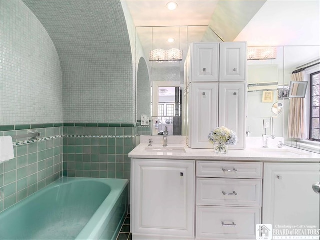 full bath with lofted ceiling, double vanity, a sink, and a garden tub