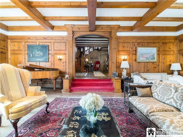 living area with stairs, beamed ceiling, wood walls, and wood finished floors