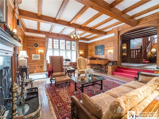 living room featuring hardwood / wood-style floors, wood walls, beamed ceiling, and an inviting chandelier