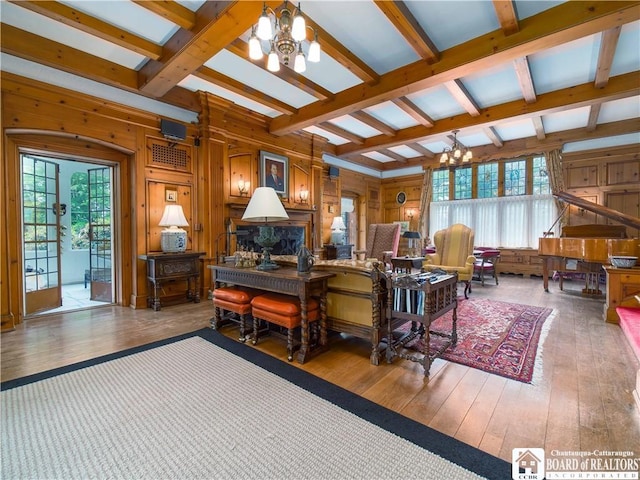 interior space featuring a healthy amount of sunlight, beamed ceiling, wood-type flooring, and a notable chandelier