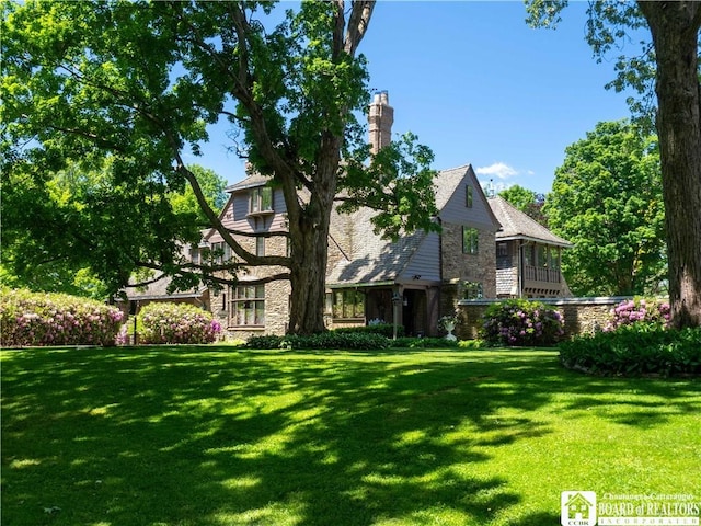 rear view of house with stone siding and a lawn