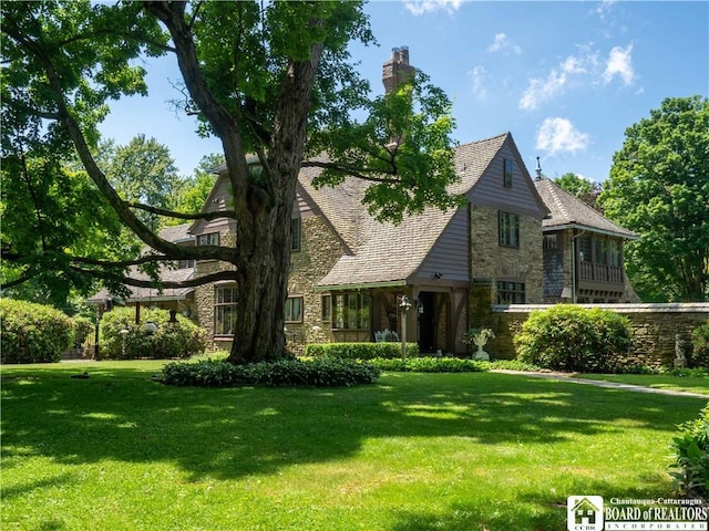 tudor-style house featuring stone siding and a front yard