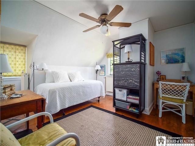 bedroom with ceiling fan, vaulted ceiling, and wood finished floors