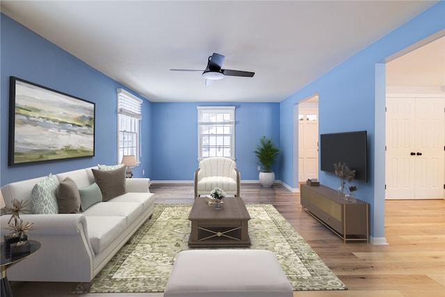 living area featuring baseboards, a ceiling fan, and wood finished floors