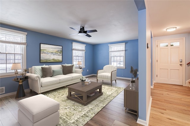 living area featuring baseboards, visible vents, ceiling fan, and wood finished floors