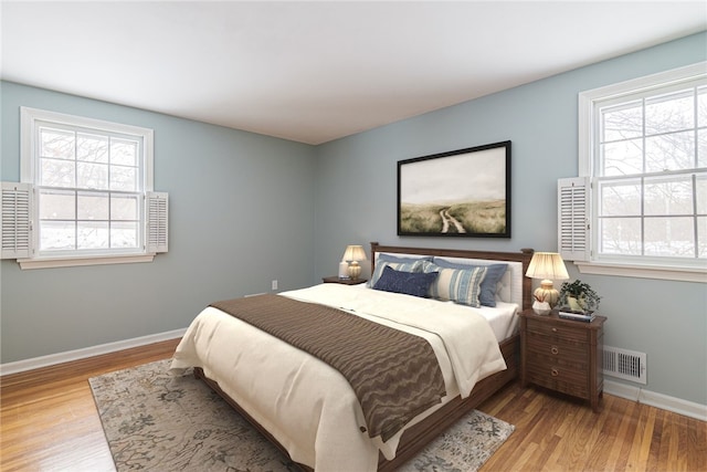 bedroom featuring wood finished floors, visible vents, and baseboards