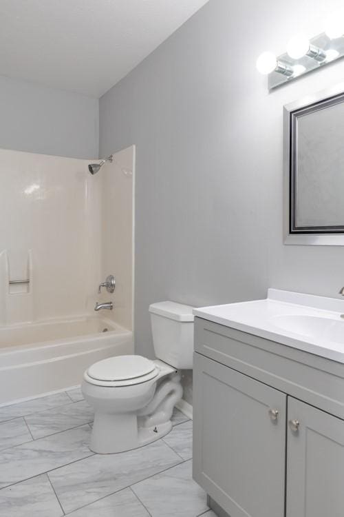 full bathroom with marble finish floor, shower / bath combination, vanity, and toilet