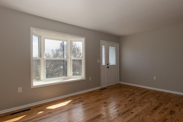 entryway with baseboards, visible vents, and wood finished floors