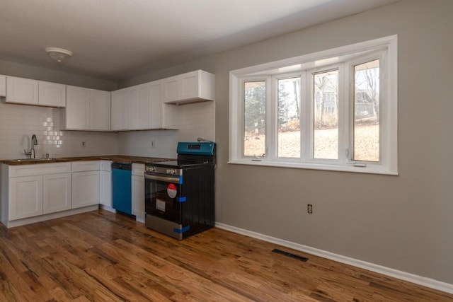 kitchen featuring dark wood-style flooring, a sink, backsplash, and stainless steel range with electric cooktop