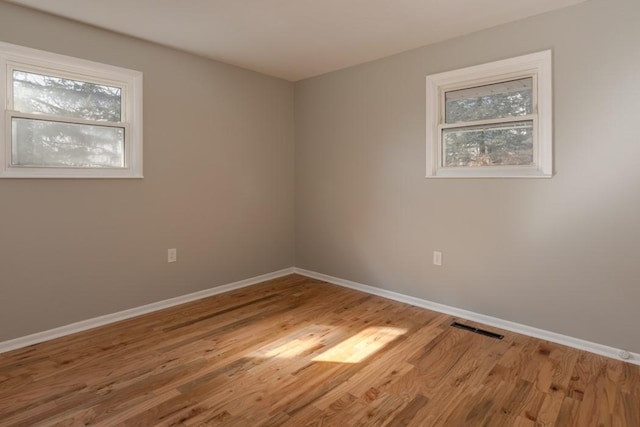 unfurnished room with baseboards, visible vents, and wood finished floors