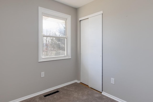 carpeted empty room featuring baseboards and visible vents