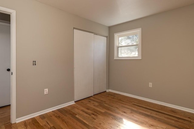 unfurnished bedroom featuring a closet, baseboards, and wood finished floors