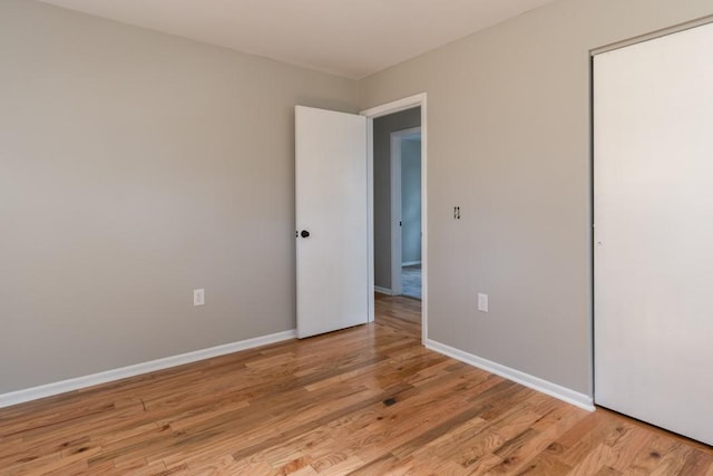 unfurnished bedroom with light wood finished floors, a closet, and baseboards