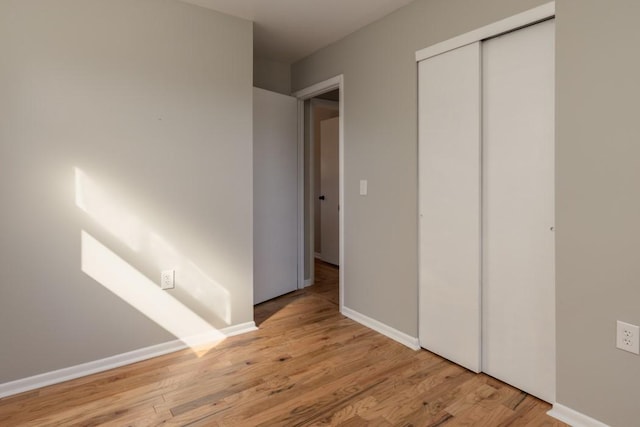 unfurnished bedroom featuring a closet, baseboards, and wood finished floors