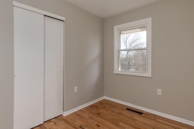 unfurnished bedroom with light wood finished floors, a closet, visible vents, and baseboards